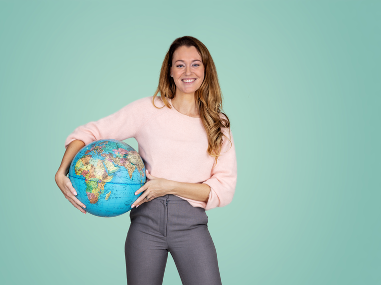 Lachende vrouw met een globe onder haar arm