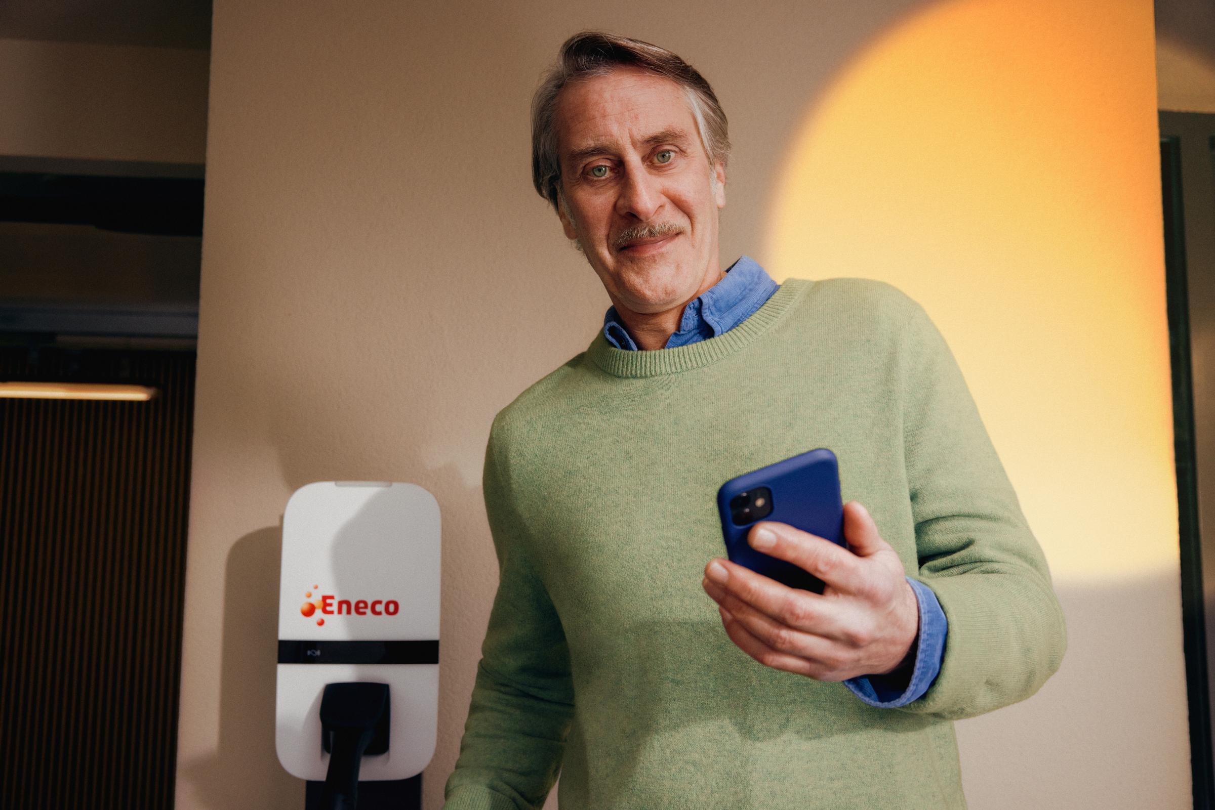 Man bij laadpaal met mobiel