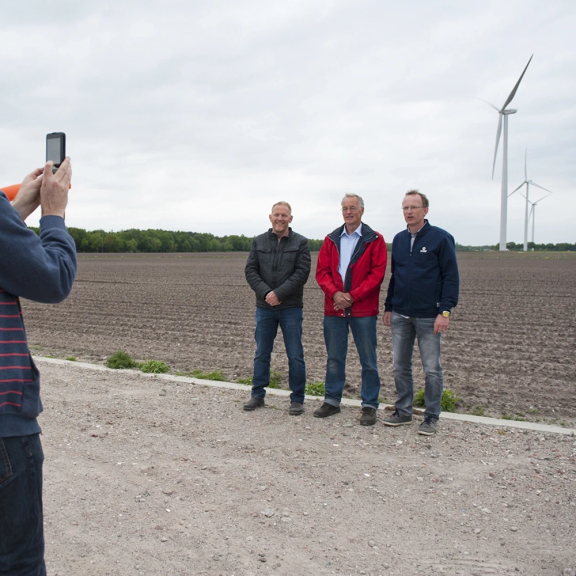 Drie mannen gaan op de foto voor een windmolen