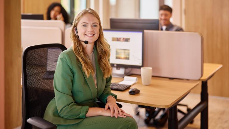 Vrouw zit aan bureau met headset op