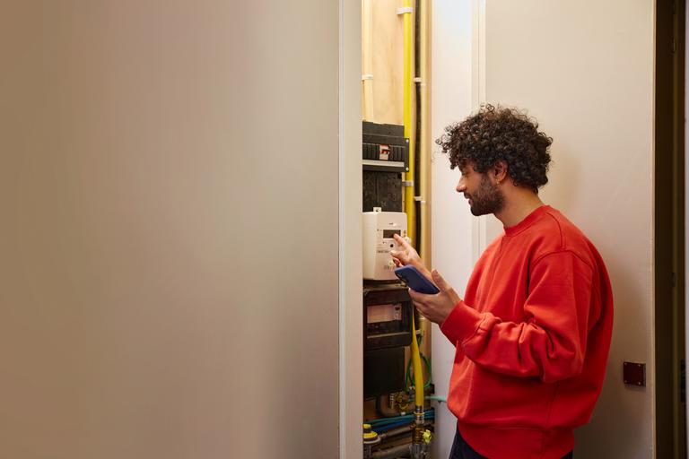 Man met telefoon bij meterkast