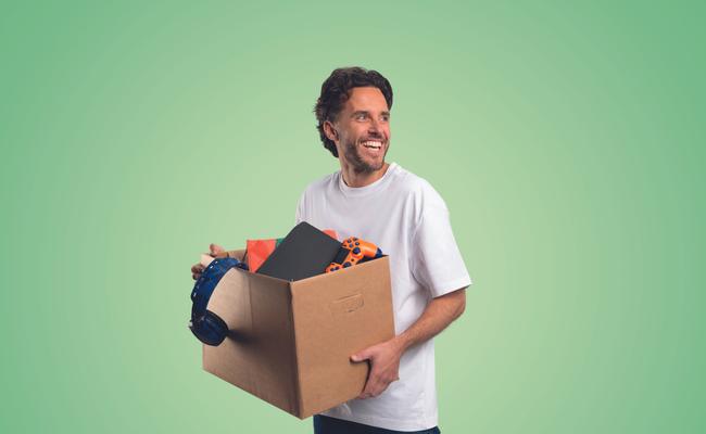 Een glimlachende man staat met een verhuisdoos in zijn handen.