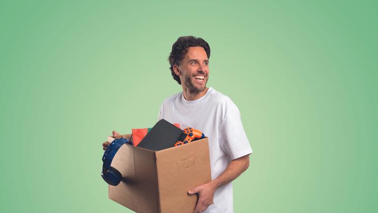 Een glimlachende man staat met een verhuisdoos in zijn handen.