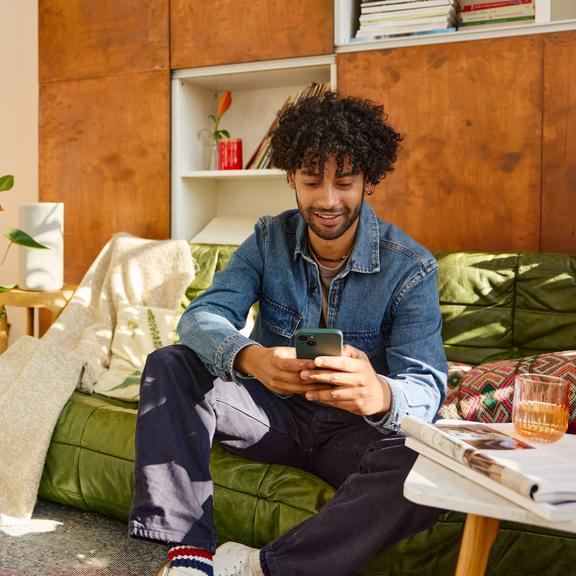 Man met smartphone op de sofa