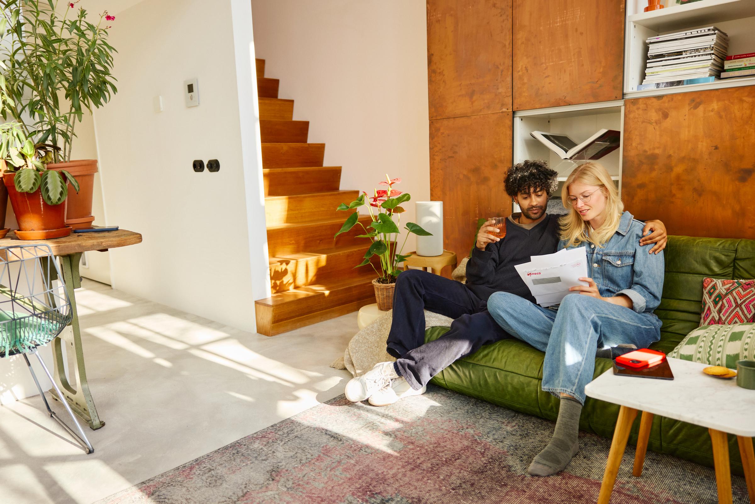 Een koppel zit in de zetel met hun Eneco facturen