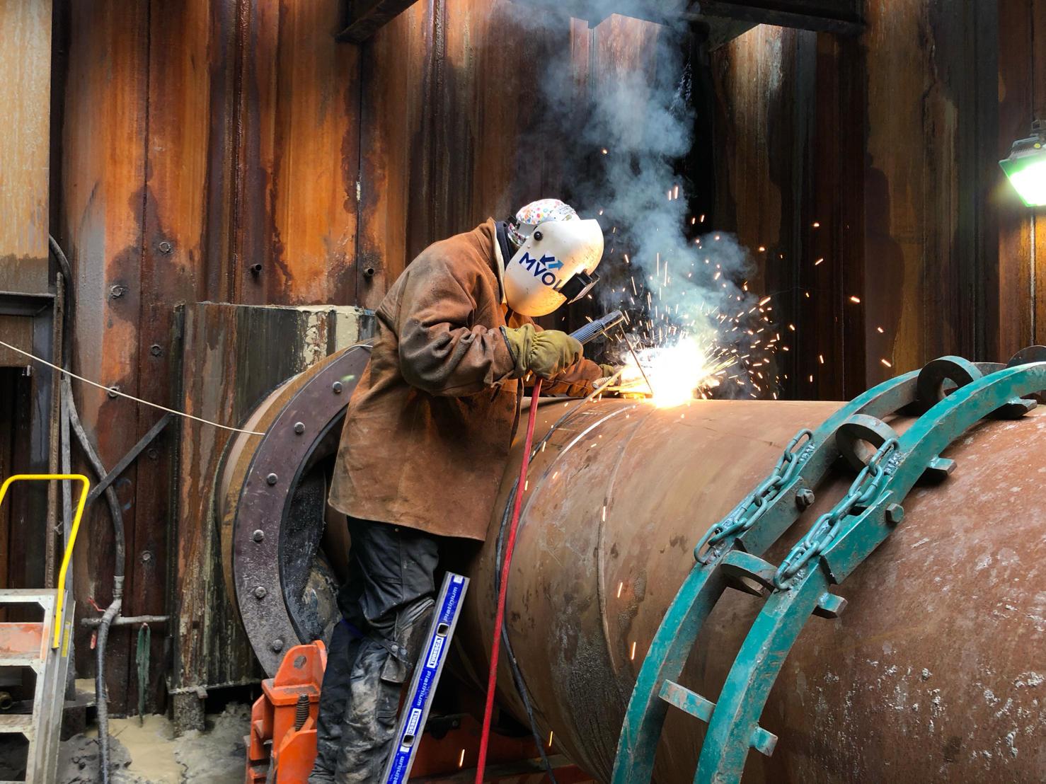 Man pleegt onderhoud aan ijzeren buis