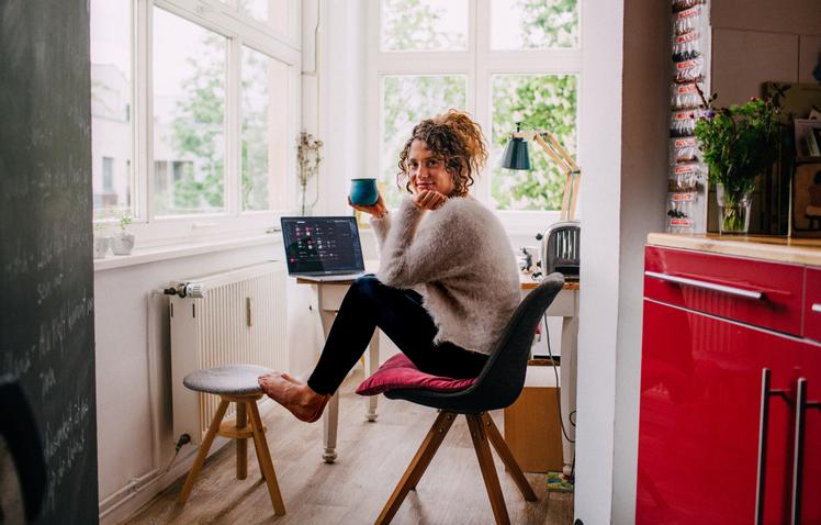 Vrouw achter de laptop met een kopje koffie in haar hand
