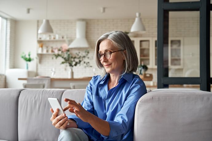 Vrouw zit op de bank met haar telefoon