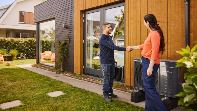 Monteur en klant schudden de hand voor een hybride warmtepomp