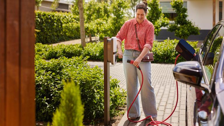 Vrouw laadt haar elektrische auto op aan een laadpaal