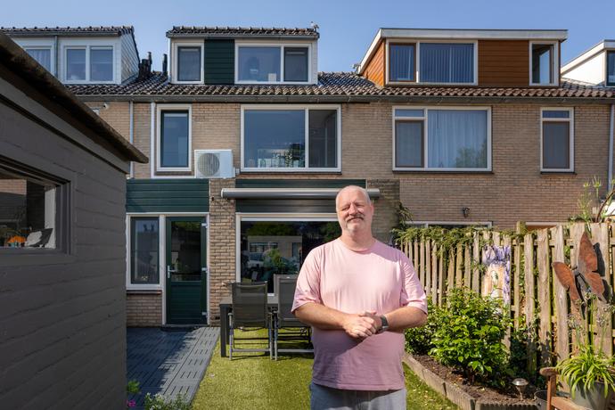 Klant Marco in de achtertuin van zijn woning met op de achtergrond de warmtepomp