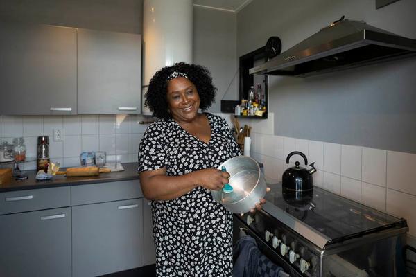 Vrouw staat in de keuken met een pan