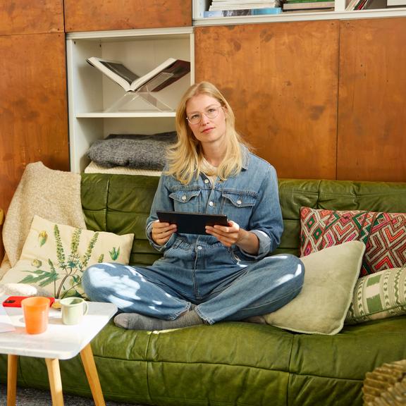 Vrouw zit met tablet op de sofa