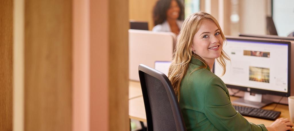 Vrouw zit aan bureau met computer