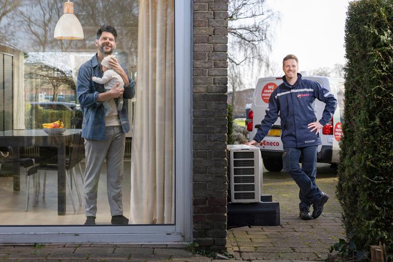 Klant met baby in de arm naast een hybride warmtepomp