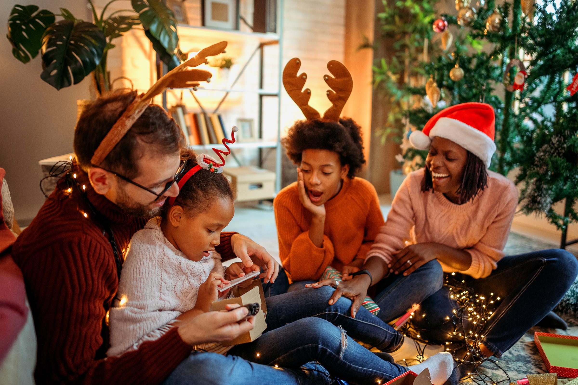Familie bij de kerstboom opent pakjes