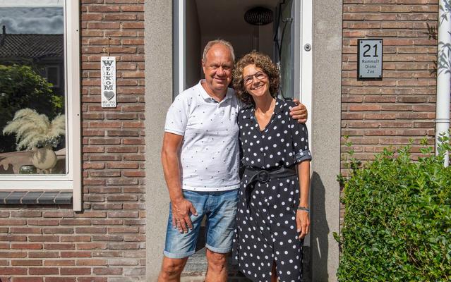 Man en vrouw poseren lachend voor hun voordeur