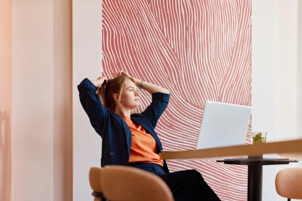 Zakelijke vrouw leunt achterover in haar stoel achter haar laptop