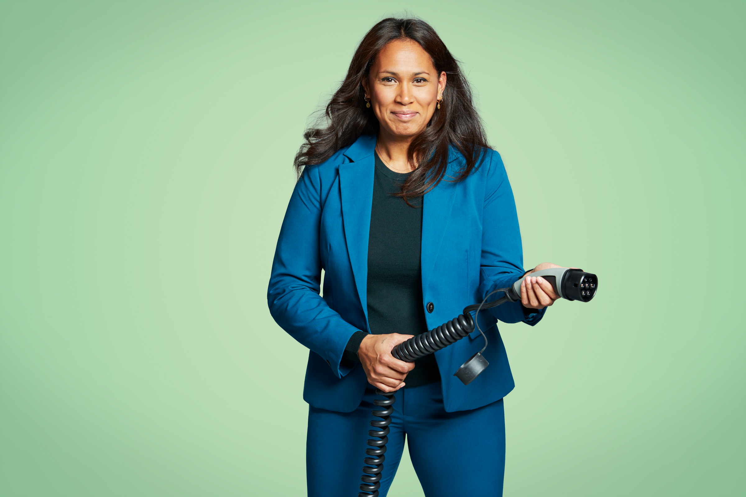 Mevrouw houdt een stekker vast om haar auto elektrisch te laden