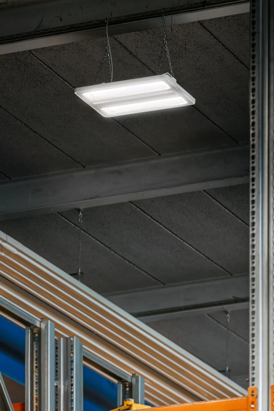 Industriehalle mit gelbem Demag-Brückenkran (40t), blauen Stahlträgern und moderner LED-Beleuchtung. Im Vordergrund sind große Kabelrollen und Maschinen sichtbar, die eine produktive Arbeitsumgebung darstellen.
