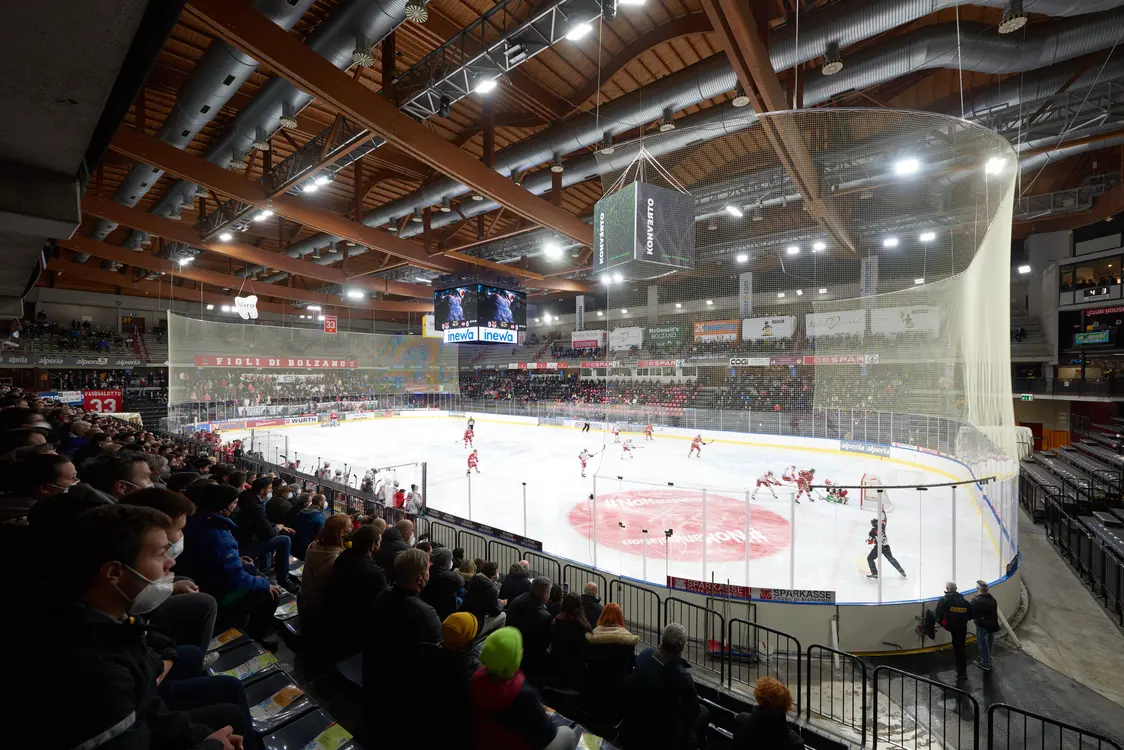 Partita di hockey su ghiaccio indoor con giocatori sul campo e tifosi sugli spalti
