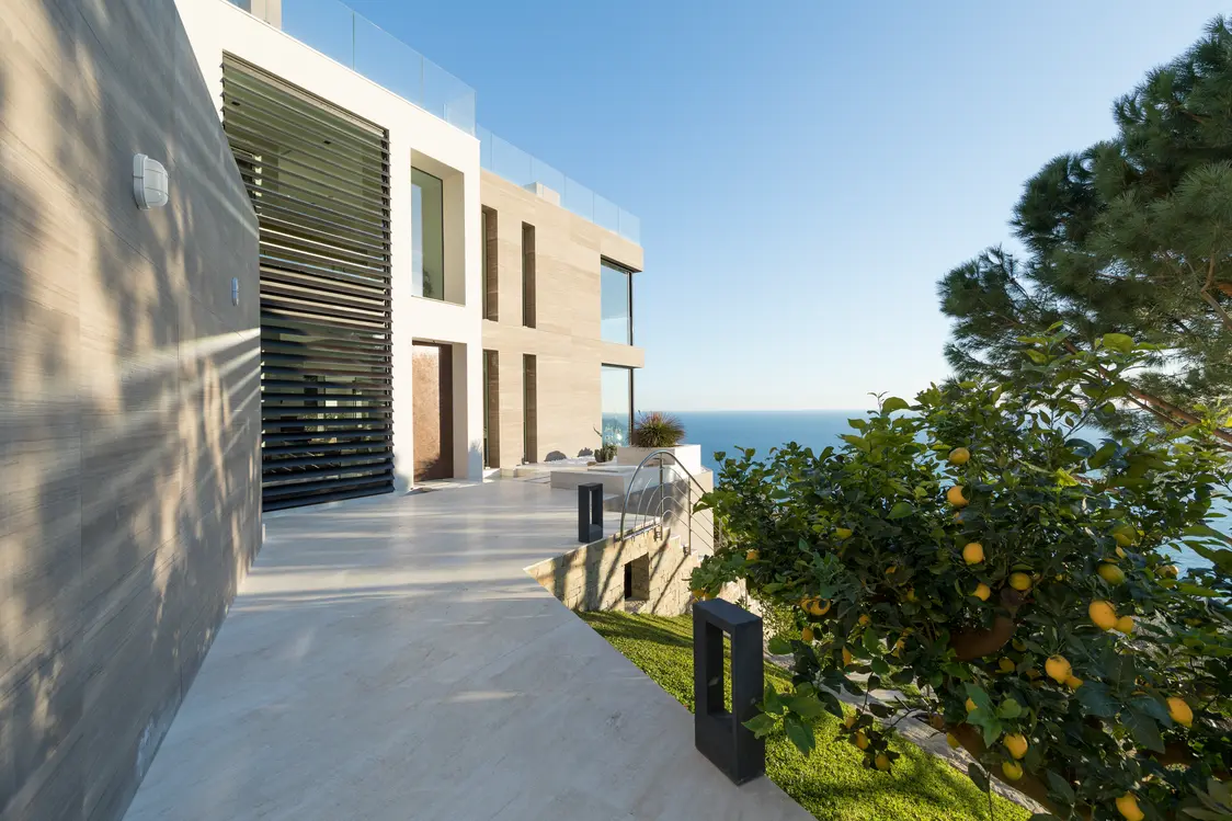 Moderne Villa mit Meerblick und Zitronenbaum im Garten, beleuchtet von Zumtobel