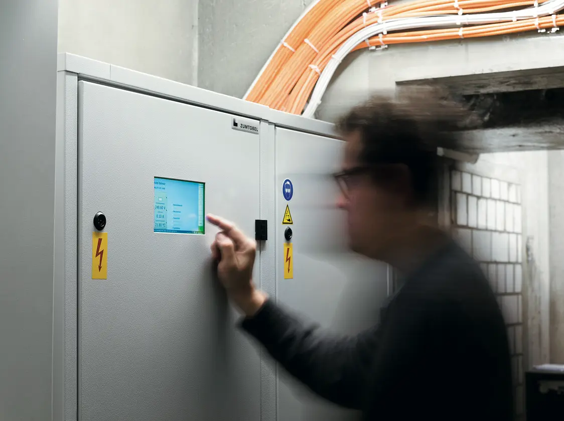 The ONLITE central CPS is a grey control cabinet housing with a small display for controlling and monitoring emergency lighting systems.