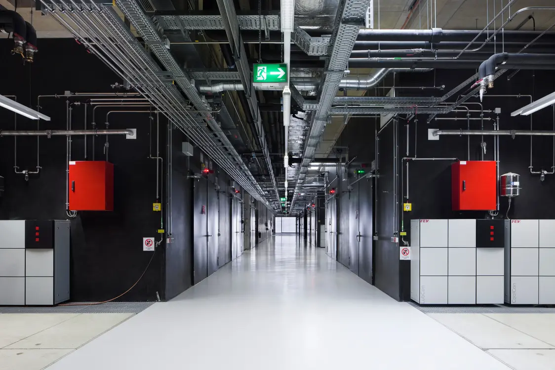 Industrieller Technikflur mit sichtbarer Gebäudetechnik und TECTON Lichtbandsystem – präzise Beleuchtung für technische Arbeitsbereiche.
