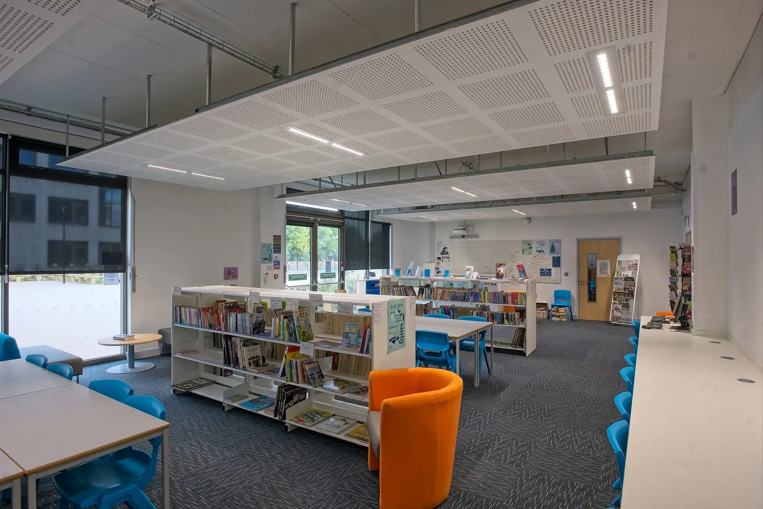Una biblioteca moderna con illuminazione brillante, sedute colorate e scaffali ben organizzati, che crea uno spazio di apprendimento accogliente e funzionale. Il design enfatizza comfort, accessibilità e produttività.