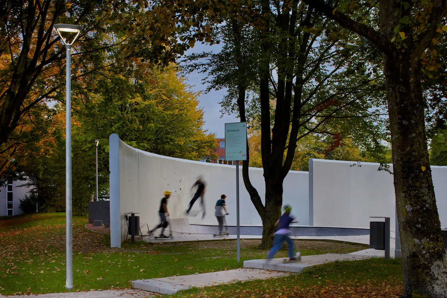 Ein von Bäumen umgebener Skatepark ist gut beleuchtet, was den Aktivitätsbereich hervorhebt und die Sicherheit der Nutzer bei Nacht erhöht.