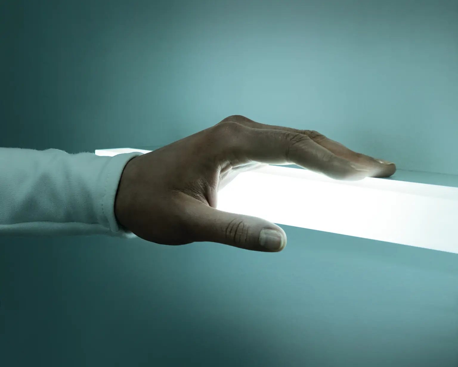 One hand touches a line of light. 