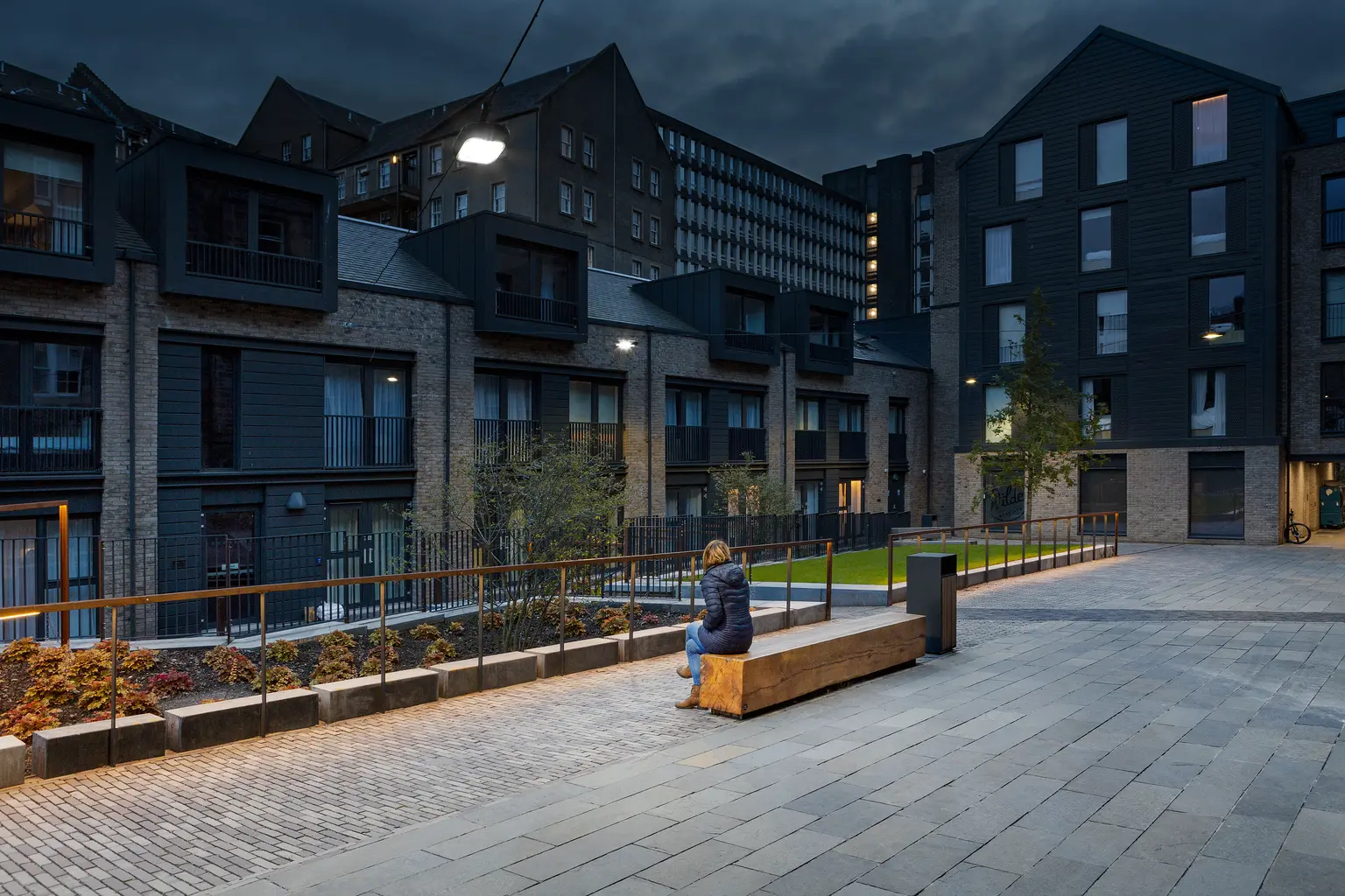 Benches and landscaped areas are highlighted by gentle lighting, creating inviting spots for rest and social interaction after dark