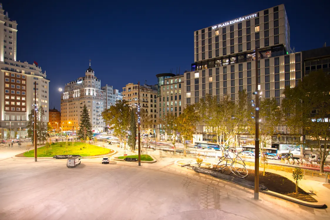 La piazza della città è illuminata da moderni e alti lampioni che forniscono un'illuminazione brillante e uniforme, migliorando la sicurezza e creando un'atmosfera notturna vivace per i pedoni e il traffico.