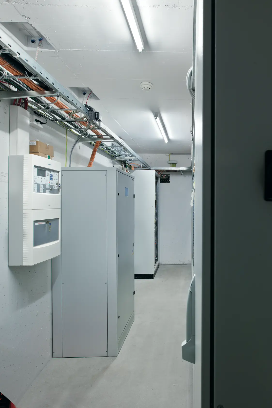 Il sistema di gestione della luce ONLITE central CPS in un locale tecnico con quadri di distribuzione e cavi sul soffitto e sulle pareti.