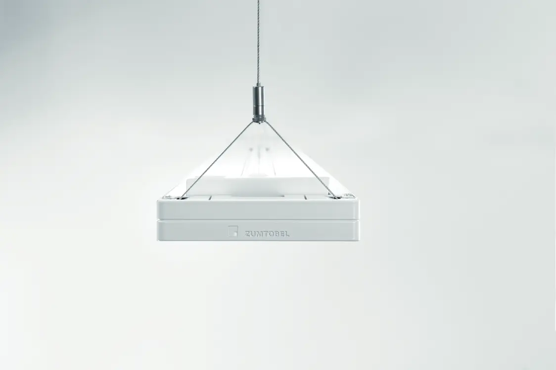 Il sistema di illuminazione CLARIS di Zumtobel è sospeso su cavi e offre un'estetica minimalista con linee pulite in uno spazio neutro.