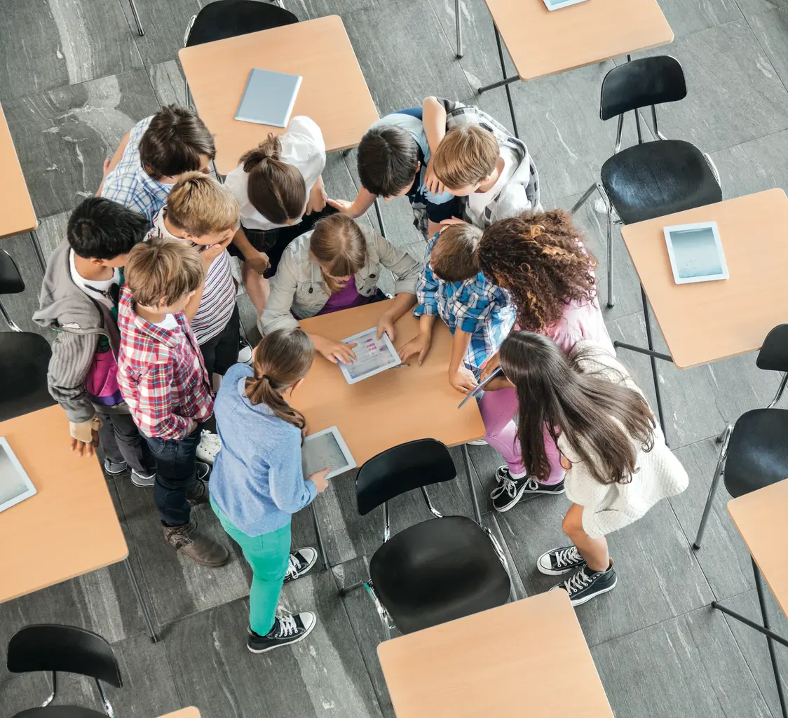 Aula di scuola elementare con i bambini rannicchiati attorno a un banco insieme