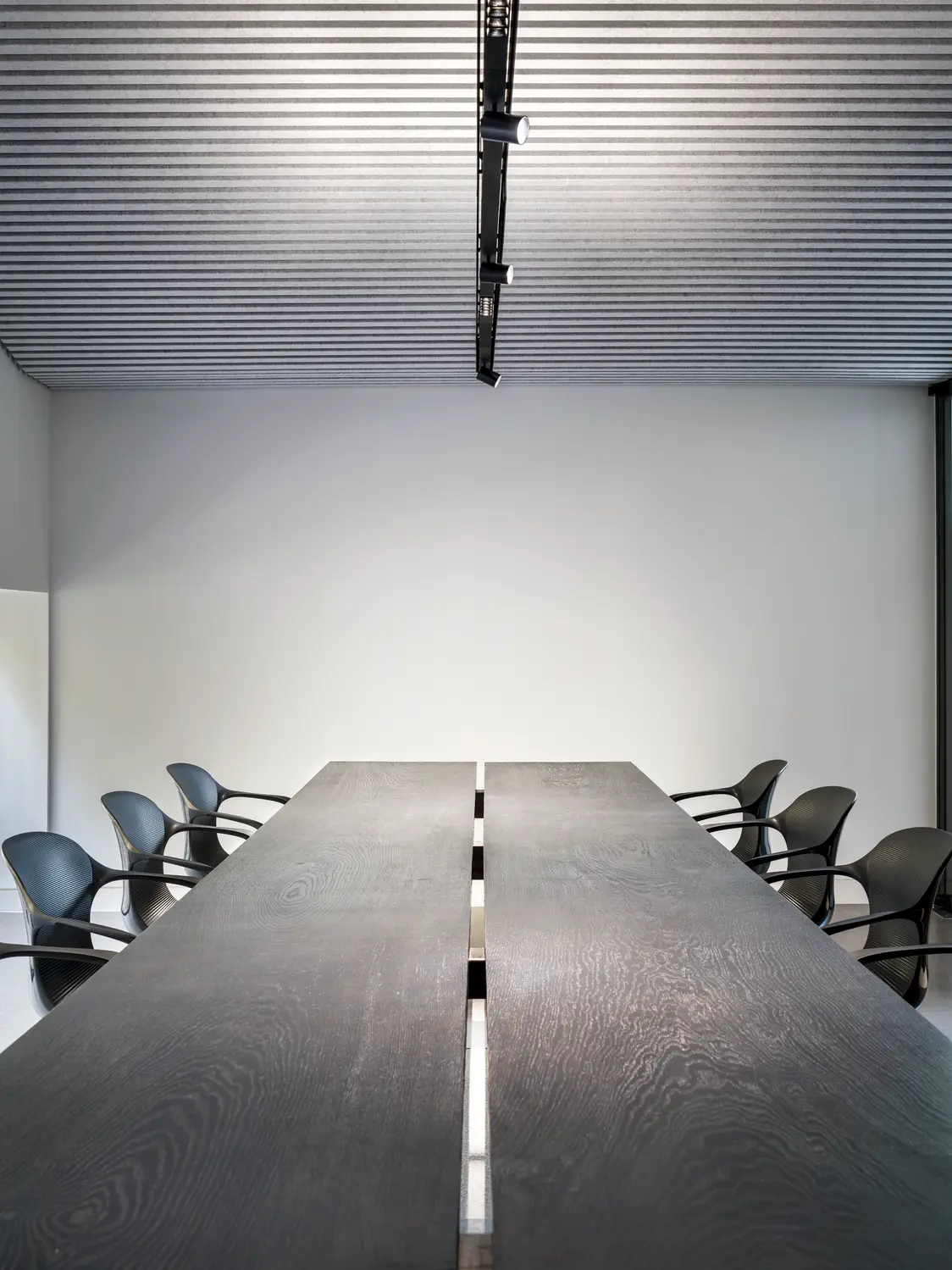 SUPERSYSTEM II beleuchtet einen modernen Konferenzraum mit dunklem Holztisch und schwarzen Stühlen gleichmäßig und blendfrei von der Decke aus.
