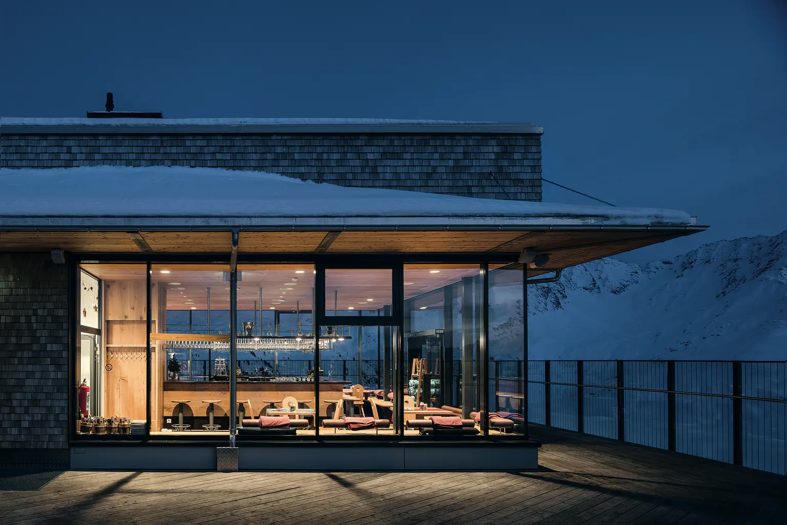 Beleuchtetes modernes Gebäude in verschneiter Berglandschaft bei Nacht Zumtobel
