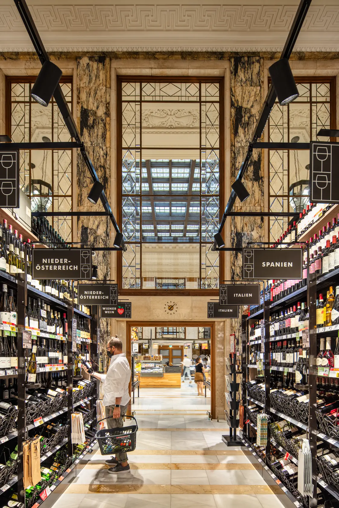 Il sistema di illuminazione TRACKS garantisce una luce uniforme in un'elegante enoteca con scaffali in legno e colonne in marmo.
