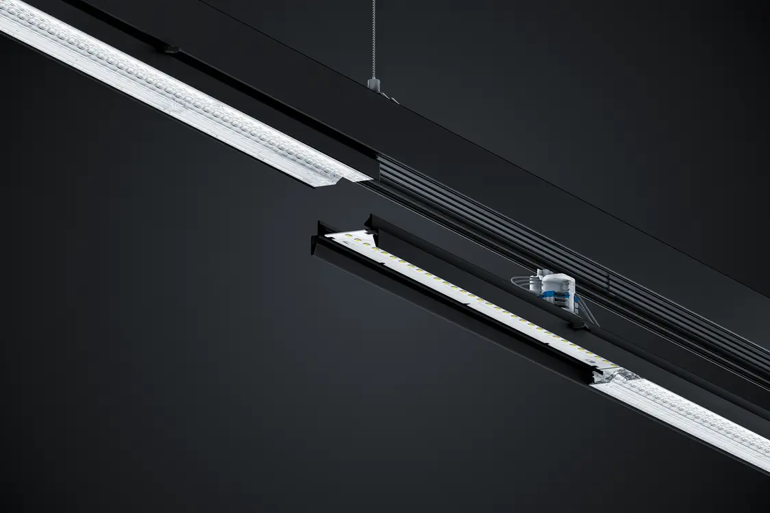  La barra luminosa a LED TECTON illumina una stanza moderna in cui un uomo è in piedi davanti a un piano di lavoro.