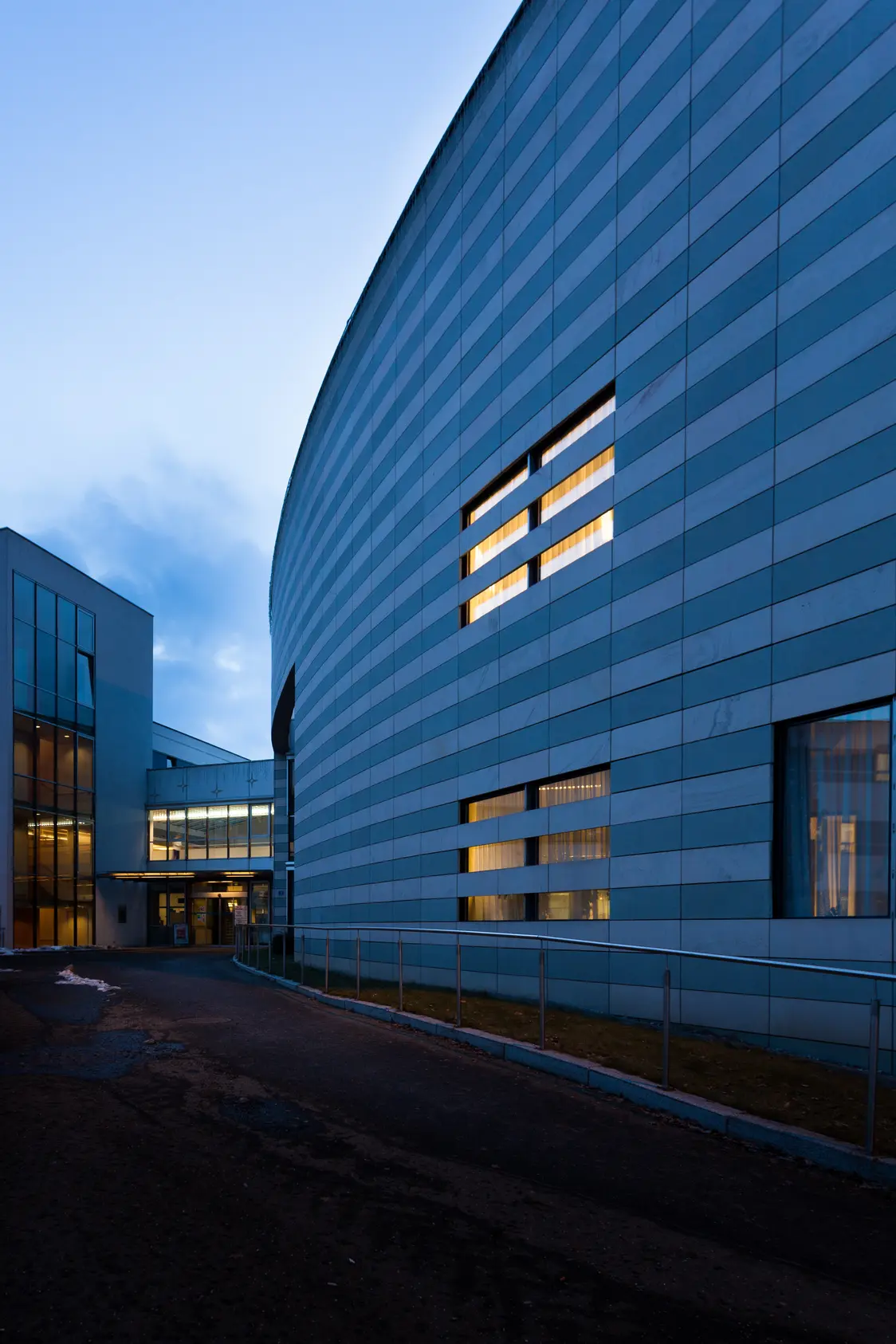 Moderne Krankenhausfassade in Bruck an der Mur bei Abenddämmerung mit beleuchteten Fenstern und geschwungener Architektur