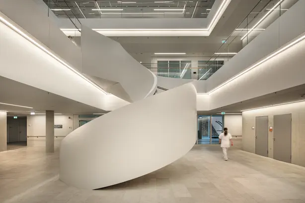 Eine Runde Treppe im Unfallkrankenhaus Berlin mit Lichtleisten an den Rändern und Geländern.