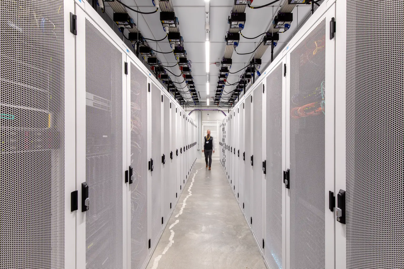 Interno di una sala di colocation del data center di Kao con gabbie metalliche sicure per server, cablaggio strutturato e apparecchiature di rete.