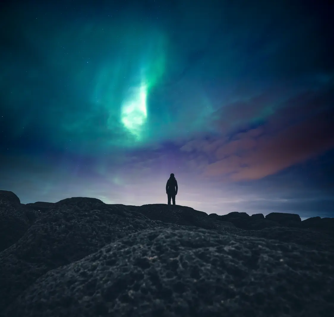 Aurora boreale, luci polari o luci del nord e una persona nel cielo notturno sopra l'isola di Senja, nella Norvegia settentrionale.