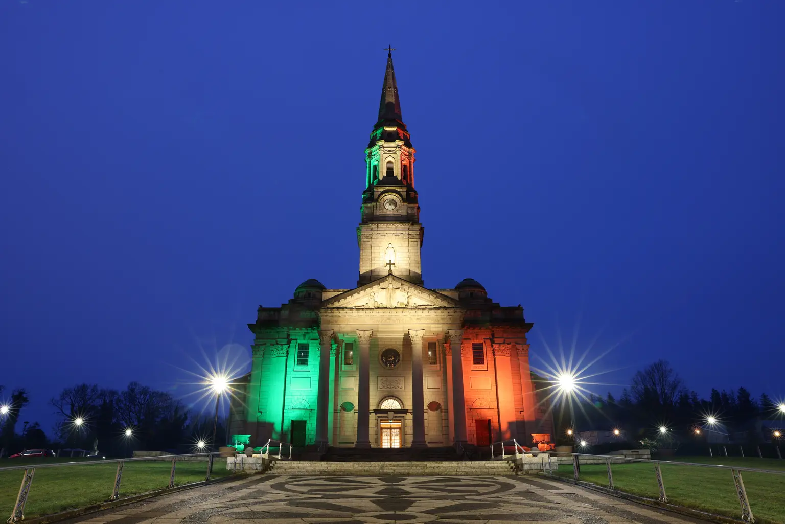 Dynamische Außenbeleuchtung taucht die Kirchenfassade in lebendige Farben, wodurch das Gebäude nachts zu einem markanten Wahrzeichen wird und je nach Anlass unterschiedliche Lichtstimmungen ermöglicht.