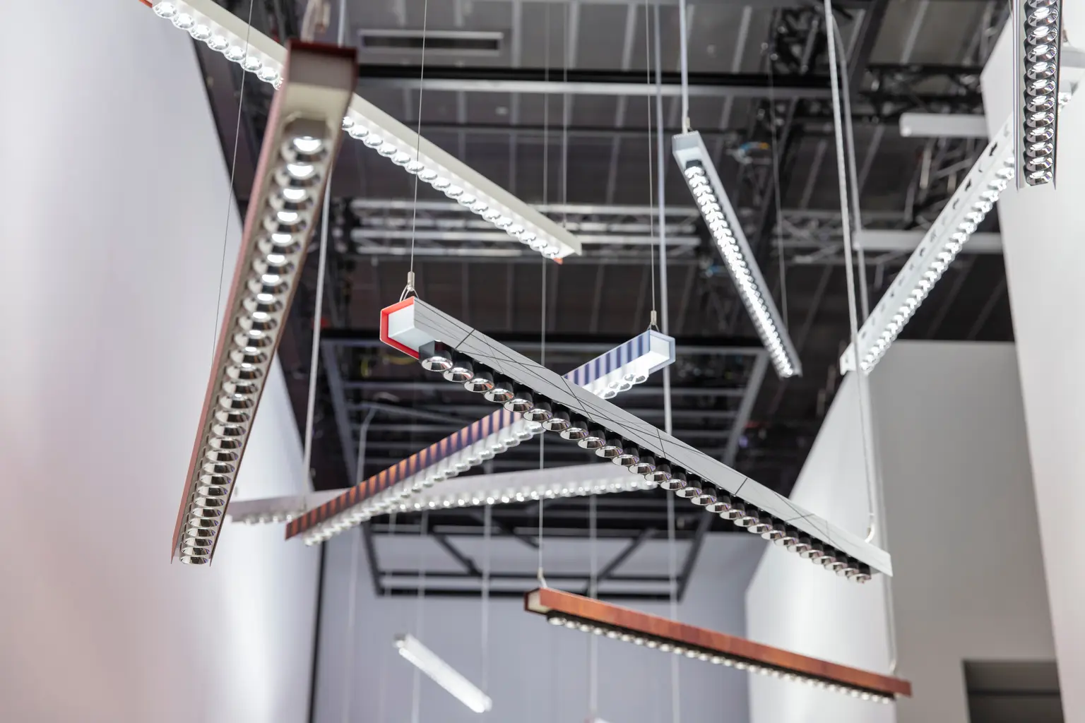 Diversi apparecchi IZURA di Zumtobel sono appesi in un ambiente moderno in uno spazio dal soffitto aperto.