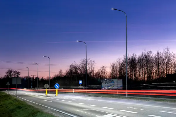Una strada a Wejherowo al crepuscolo con alberi in lontananza e un palo di illuminazione per la sicurezza