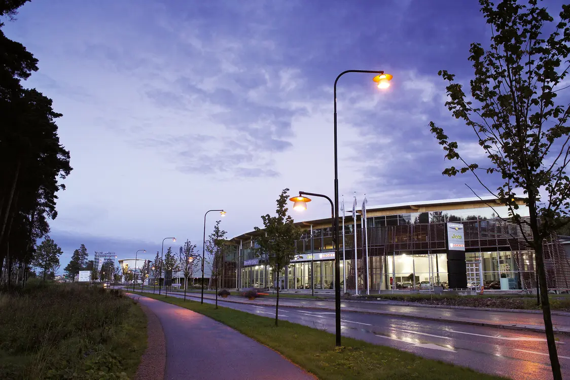 Beleuchtete Straße bei Dämmerung mit modernen Straßenlaternen und Gebäuden im Hintergrund, Zumtobel