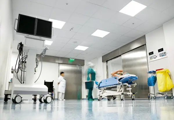 Un corridoio ospedaliero con personale del servizio sanitario nazionale presso l'ascensore con un lettino per pazienti