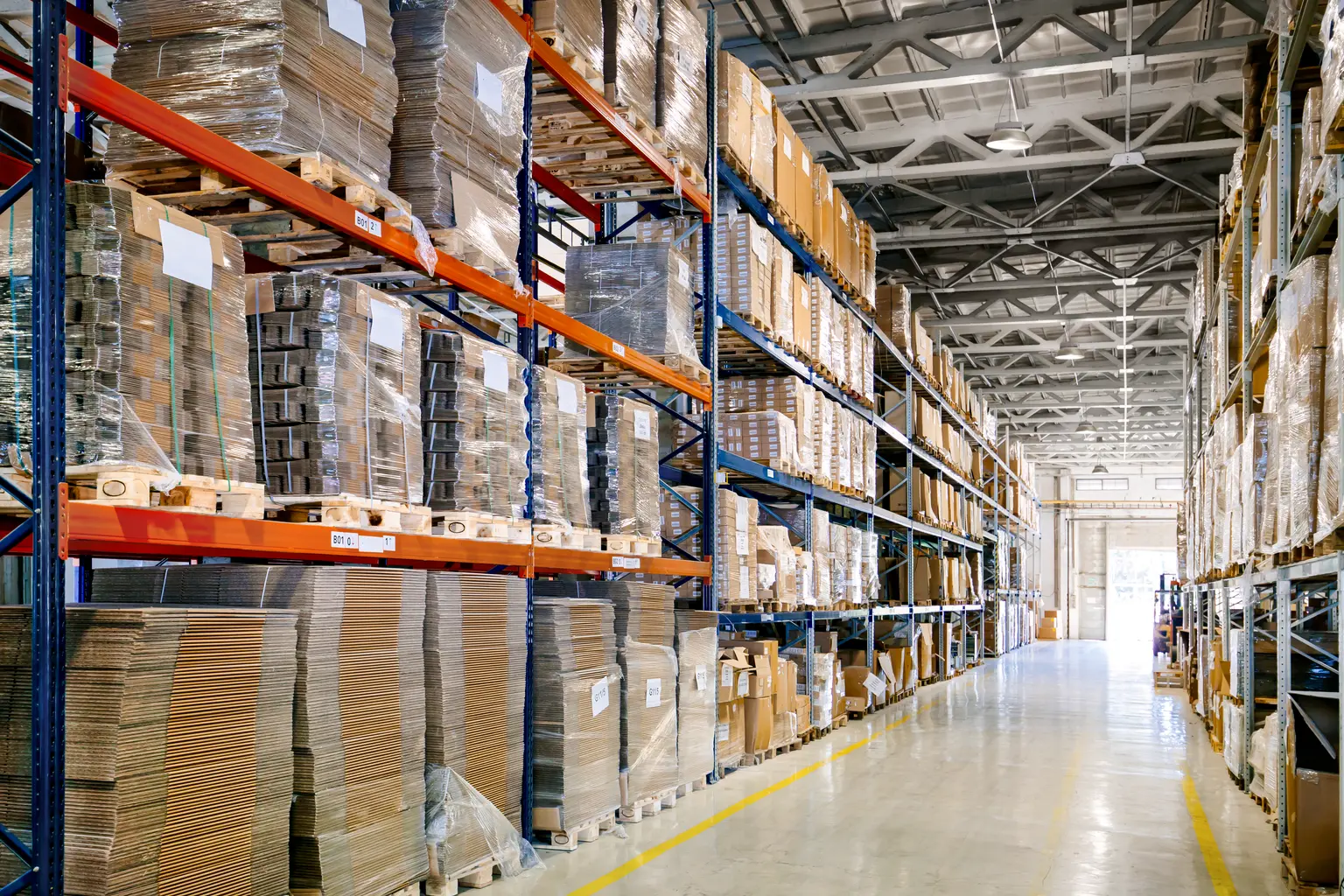 Area logistica con scaffalature alte piene di scatole e pallet, con lo spazio illuminato da Thorn Lighting